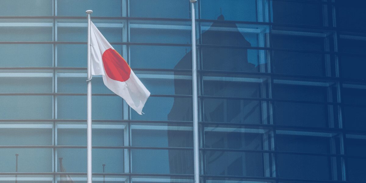 Japan's flag displayed in front of a modern glass building, symbolizing the importance of understanding the country's corporate hierarchy and business practices.