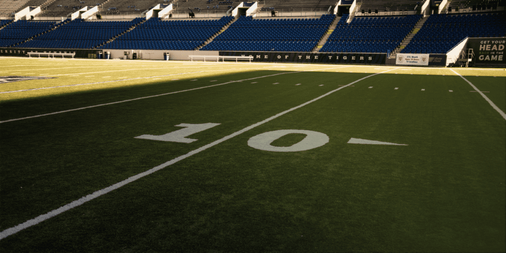 Football field darkened by a shadow, symbolizing the risk posed by this former pro-athlete to a leading bank.