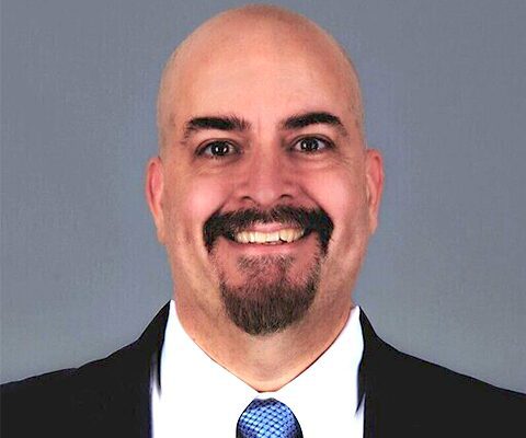Vcheck's CTO Jake Kirby, in front of a gray background.