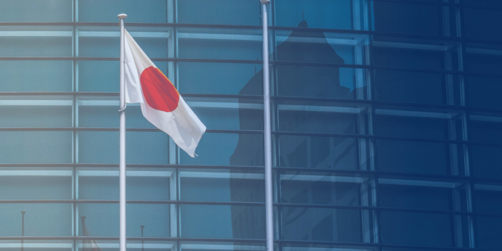 Japan's flag displayed in front of a modern glass building, symbolizing the importance of understanding the country's corporate hierarchy and business practices.