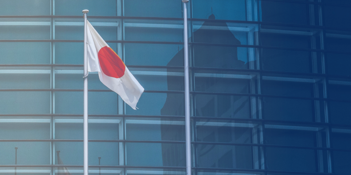 Japan's flag displayed in front of a modern glass building, symbolizing the importance of understanding the country's corporate hierarchy and business practices.