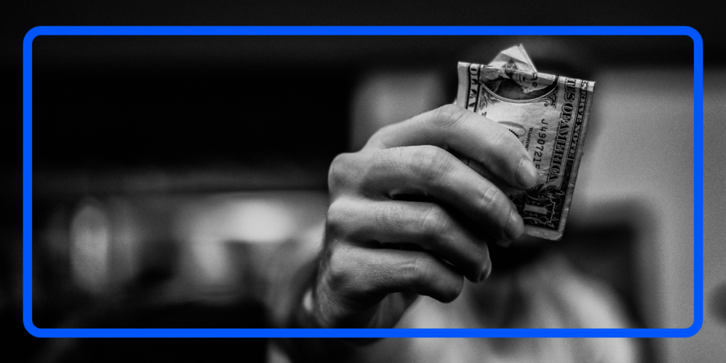 Black and white image of a person holding up cash, symbolizing the importance of due diligence in verifying bank customers to prevent financial misconduct.